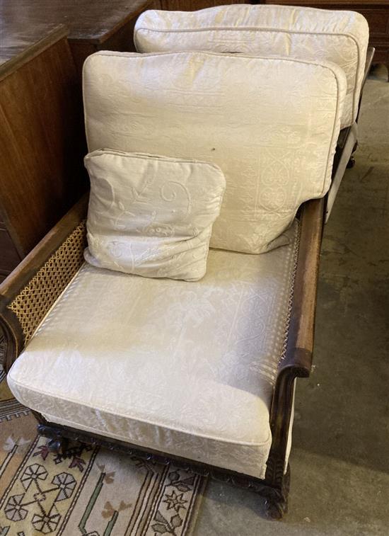 A pair of early 20th century mahogany framed bergere armchairs with caned sides, and cream brocade cushion seats and backs